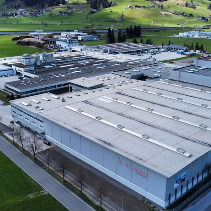 Luftaufnahme eines großen Industriekomplexes mit dem Schriftzug Atomic in ländlicher Umgebung in Salzburg oder