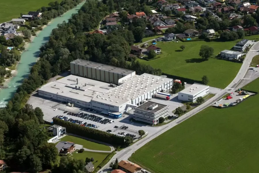 Luftaufnahme eines großen Betriebsrestaurants und Firmengeländes neben einem Fluss in einer ländlichen Region mit