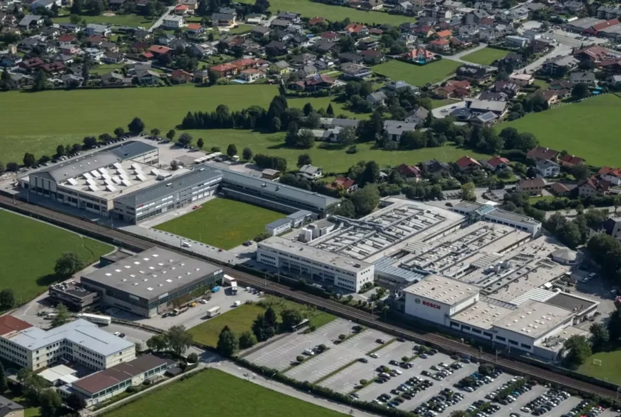 Luftaufnahme eines großen Betriebsrestaurants und Industriekomplexes mit Bosch-Logo, umgeben von Grünflächen und Wohnhäusern
